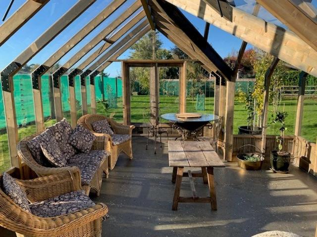 Outdoor patio area with wicker furniture and a wooden table under a wooden pergola.