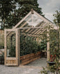 Wooden greenhouse with glass panels surrounded by trees and plants
