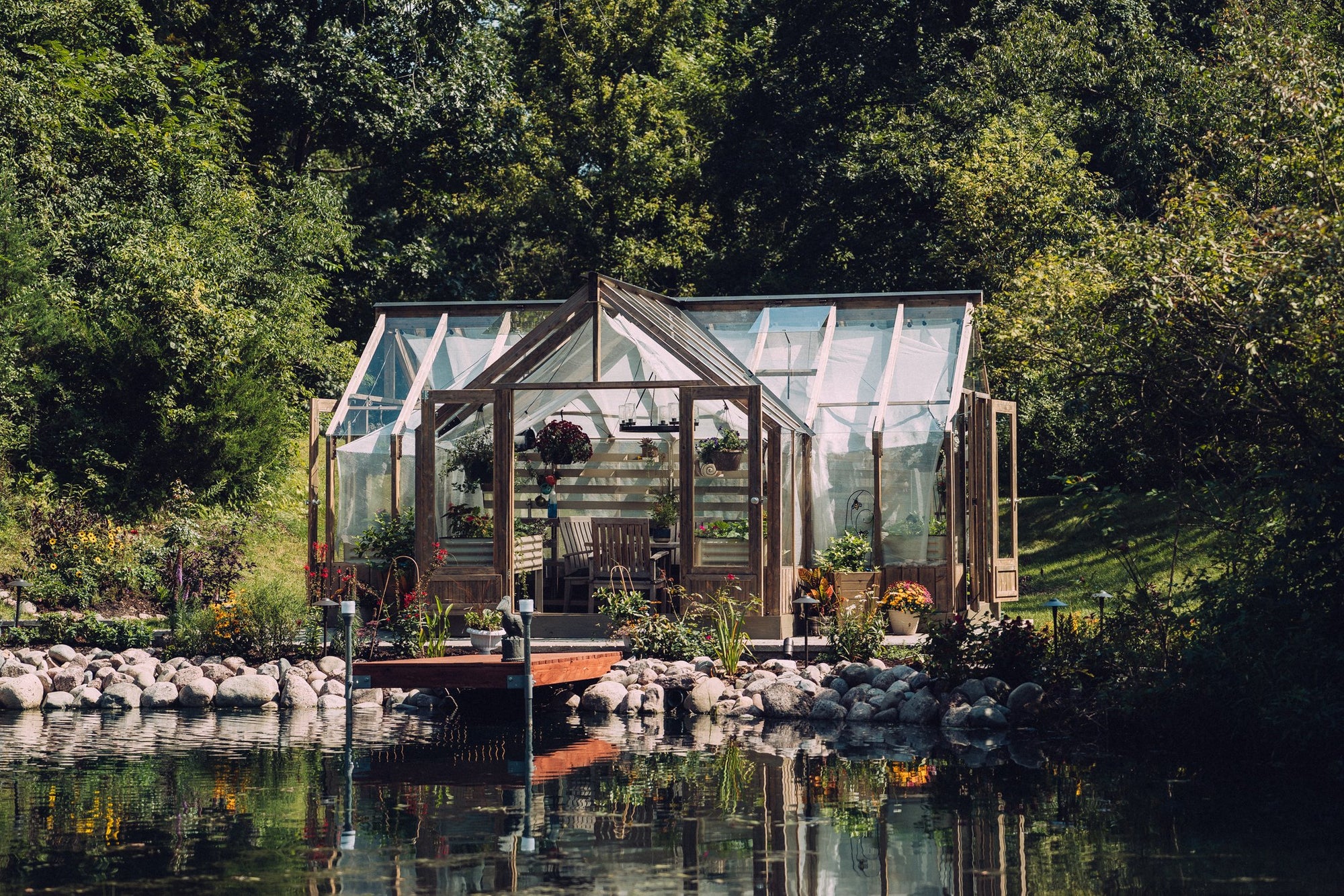 A Nordwood greenhouse with sheer curtains at the pond dock in daylight