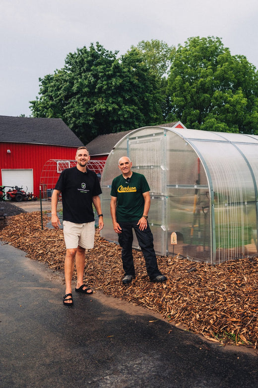 Gustavs with a New York customer at his polycarbonate greenhouse by the barn