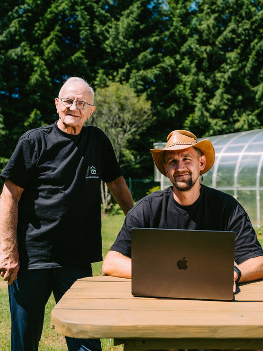 Gustavs and his father planning at the table outside their greenhouse